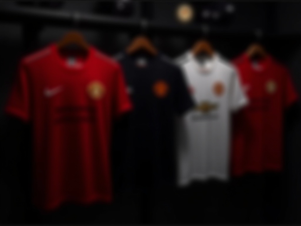 Kilka koszulek piłkarskich Manchester United ustawionych w sklepie koncepcyjnym